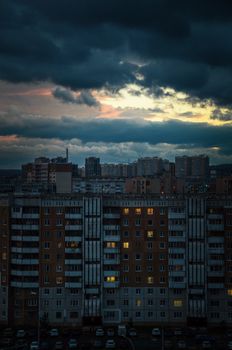 Aerial view of urban residential buildings at sunset amidst dramatic overcast skies.
