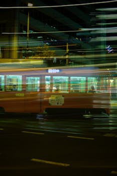 Blurred night shot capturing a moving tram in a vibrant urban cityscape.