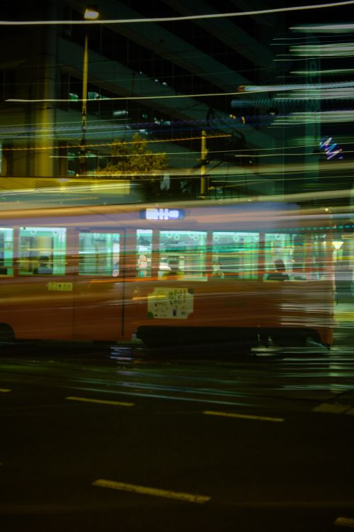 Free Blurred night shot capturing a moving tram in a vibrant urban cityscape. Stock Photo