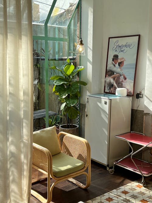 Free Rattan Armchair Next to the Fridge with a Framed Movie Poster on Top Stock Photo