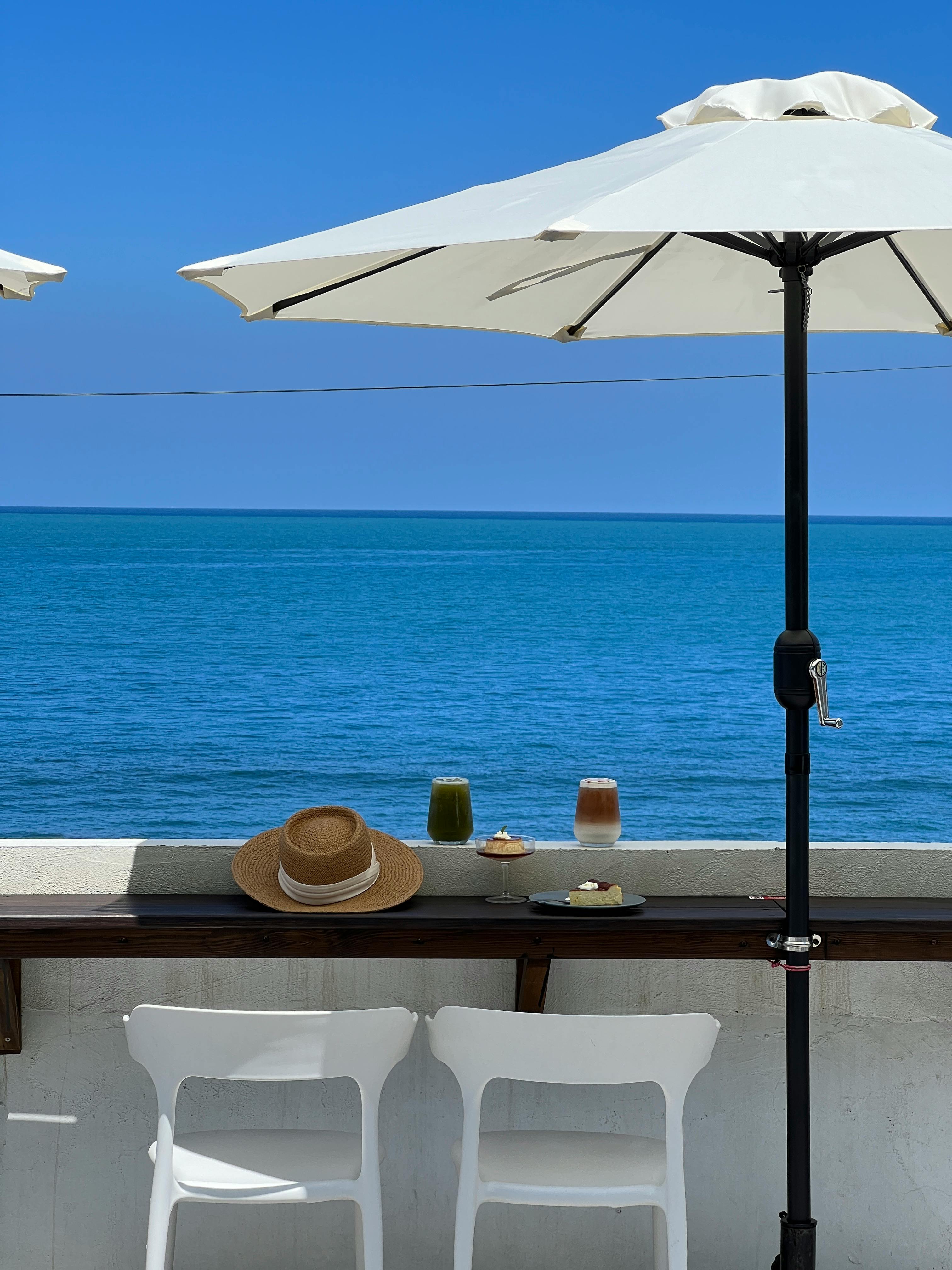 Serene ocean view with beach umbrella, chairs, and refreshing drinks.