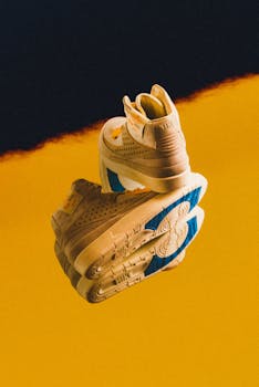 Trendy sneakers reflecting on a colorful surface, showcasing stylish footwear design.