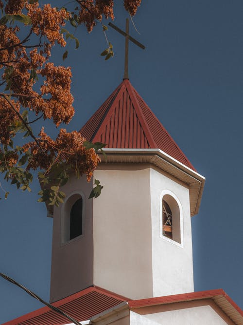 Tower of a Church with White Exterior on the Background of Blue Sky 