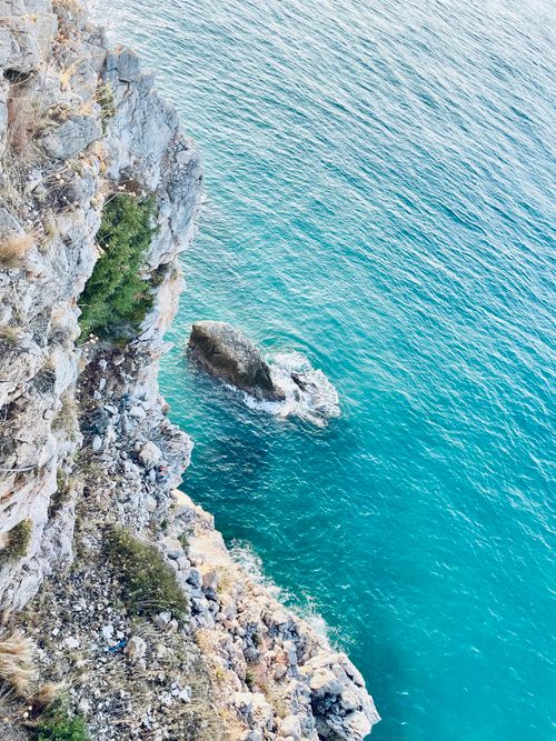 Free A stunning aerial view of rugged cliffs meeting the azure ocean, perfect for nature and travel themes. Stock Photo