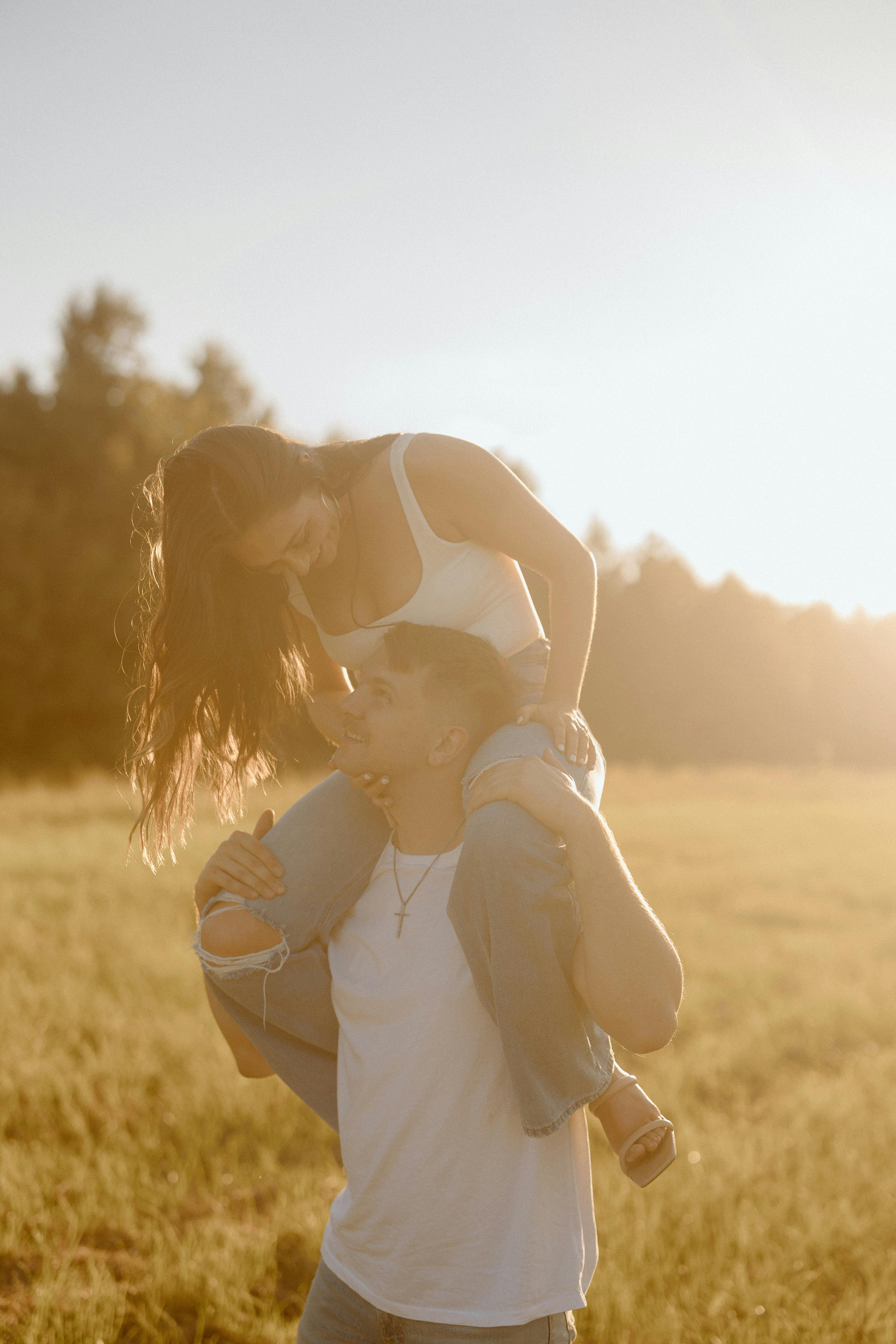 woman sitting on man at sunset