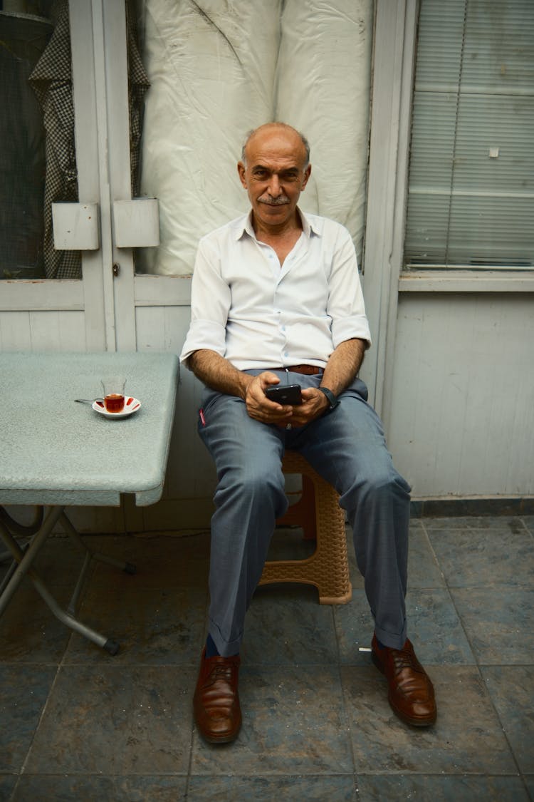 Man Sitting At The Table Outside Of A Building 