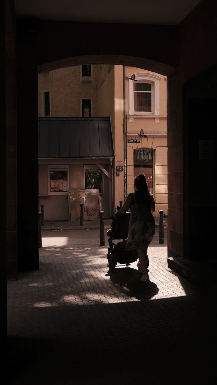 Woman With A Baby Carriage On A Street 