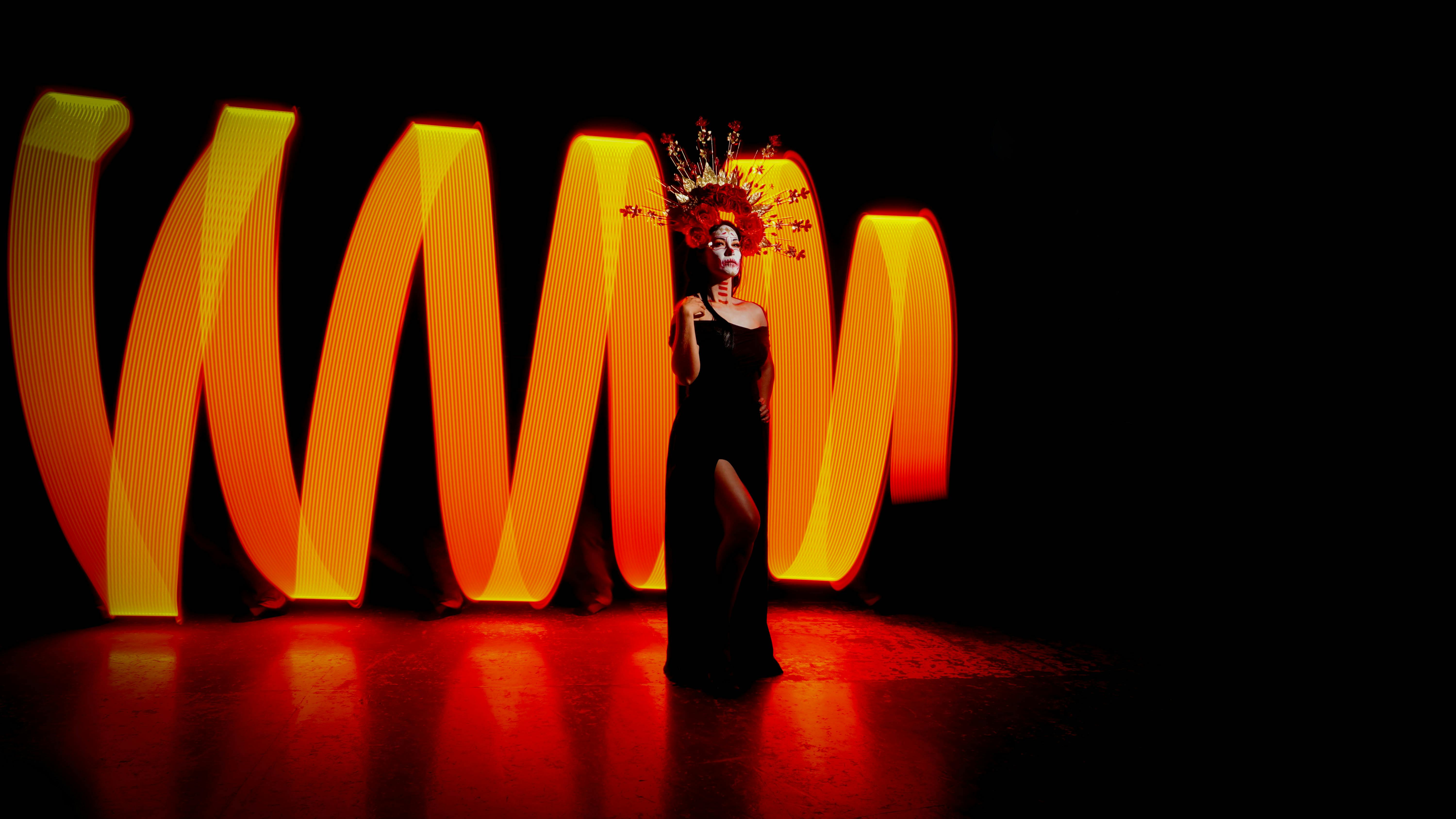 Stunning Dia de Muertos portrait with skull makeup and vibrant orange light art.