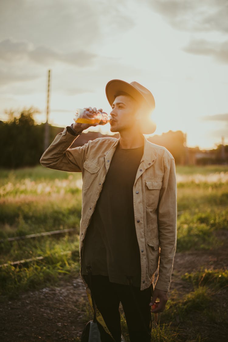 Photo Of Man Drinking Juice Outside During Golden Hour