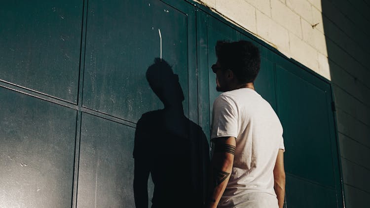 Back View Photo Of Man In White T-shirt Facing Black Gate