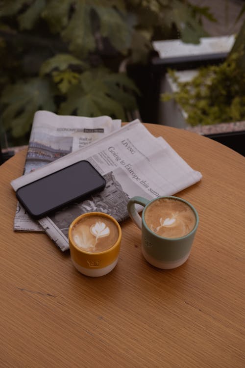 Free Coffee, Smartphone and Newspapers on Table Stock Photo