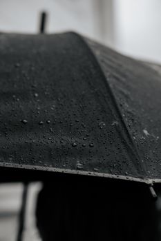 A detailed close-up of a black umbrella covered with raindrops on a rainy day in Istanbul.