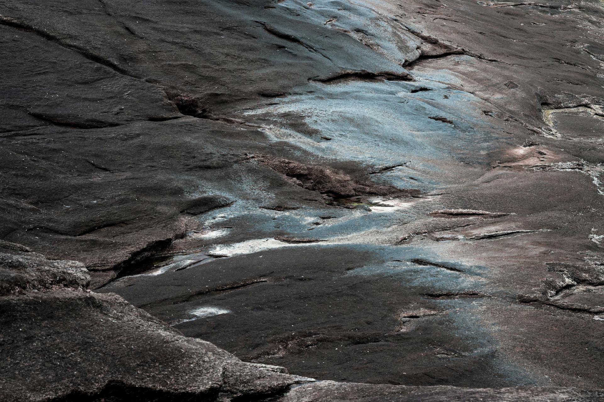 A detailed view of rough, weathered bedrock with intriguing blue hues and patterns.