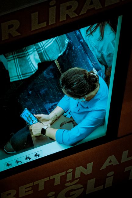 Woman sitting in transit, engaged with smartphone. Captures modern commuting lifestyle.