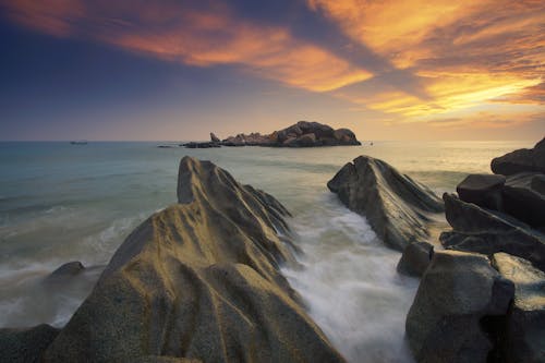 Gray Rock Formation Near Body of Water during Sunset