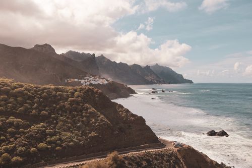Free Breathtaking view of Tenerife's rocky coastline with mountains and ocean under a partly cloudy sky. Stock Photo