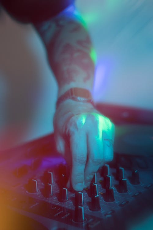 Man Turning Knobs on a DJ Mixer