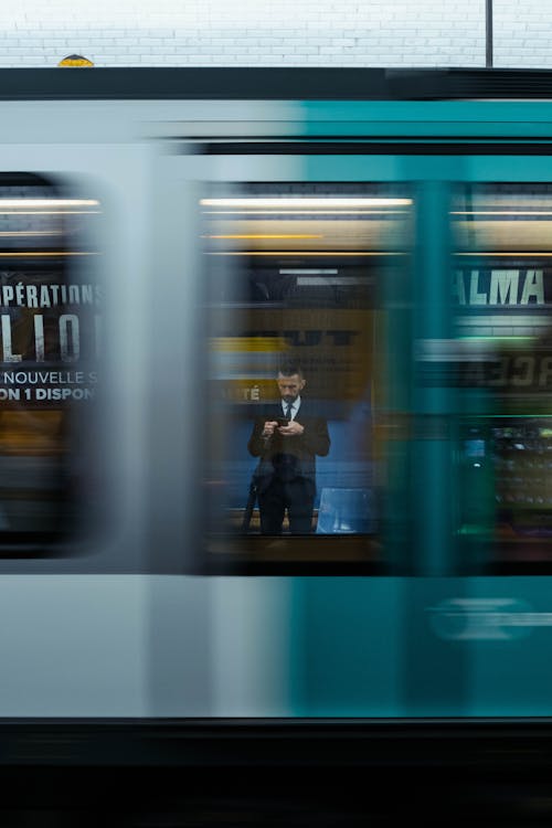 Man in a Suit Standing on a Subway Station behind a Moving Train 