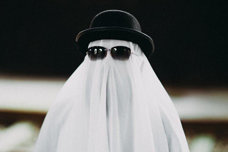 Person Dressed As A Ghost Wearing A Hat And Sunglasses