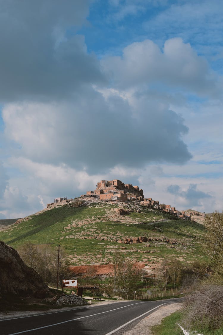 Road In Countryside With Fortification On Hill Behind