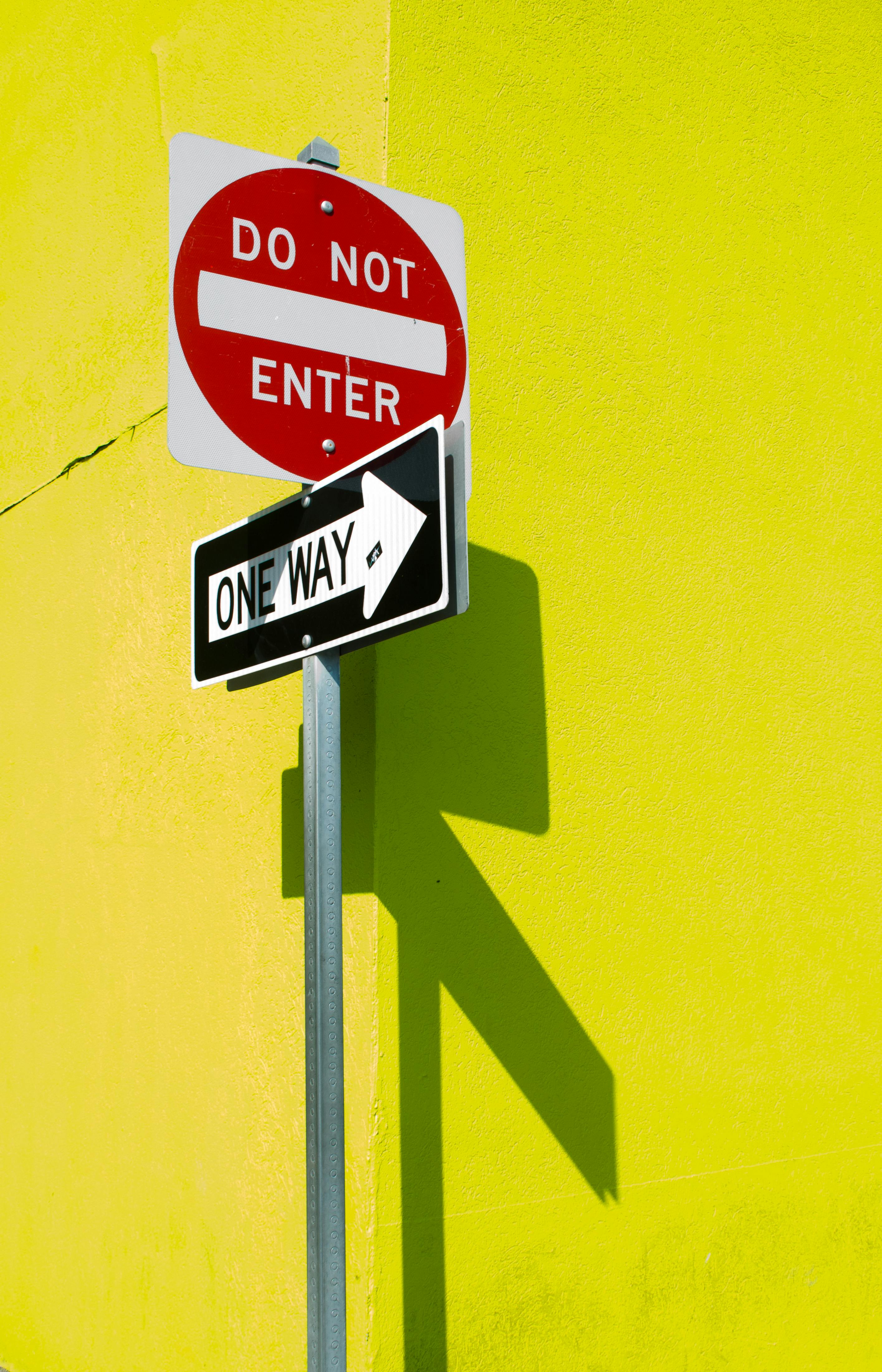 street signs casting shadow on yellow wall