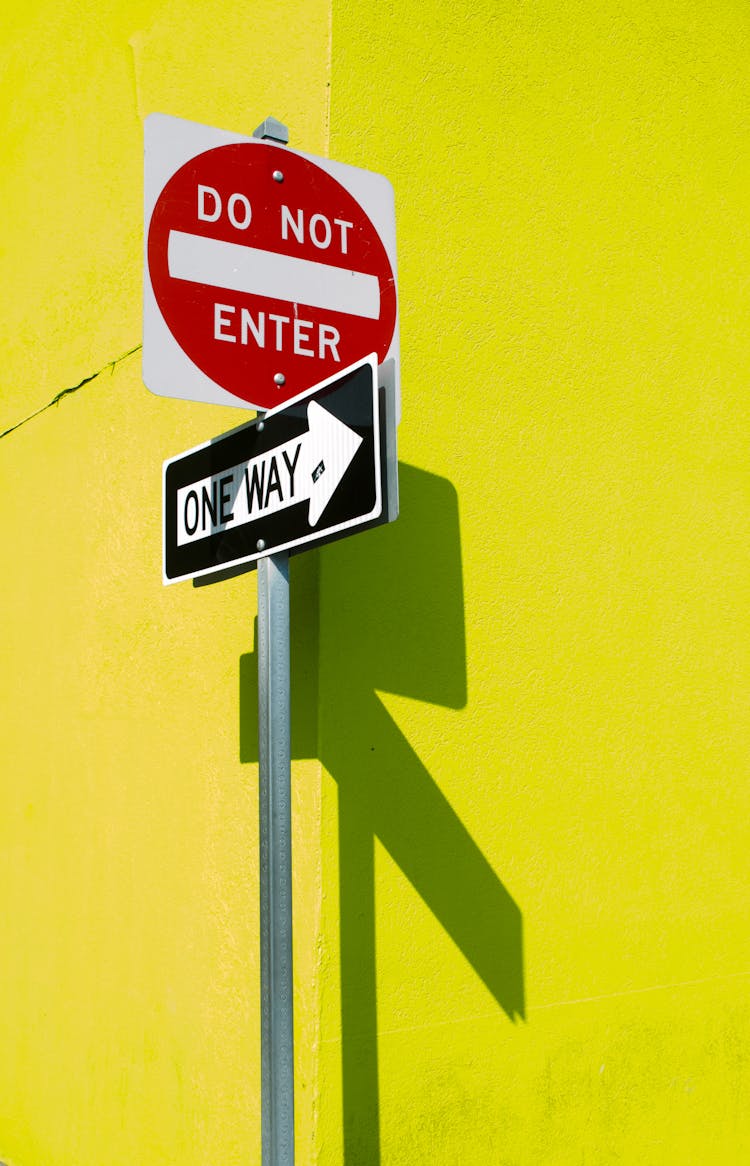 Street Signs Casting Shadow On Yellow Wall