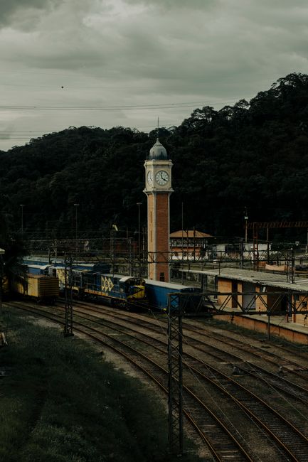 Fotomural Vista dramática de una estación de tren y torre del reloj rodeada de exuberante vegetación en São Paulo, Brasil.