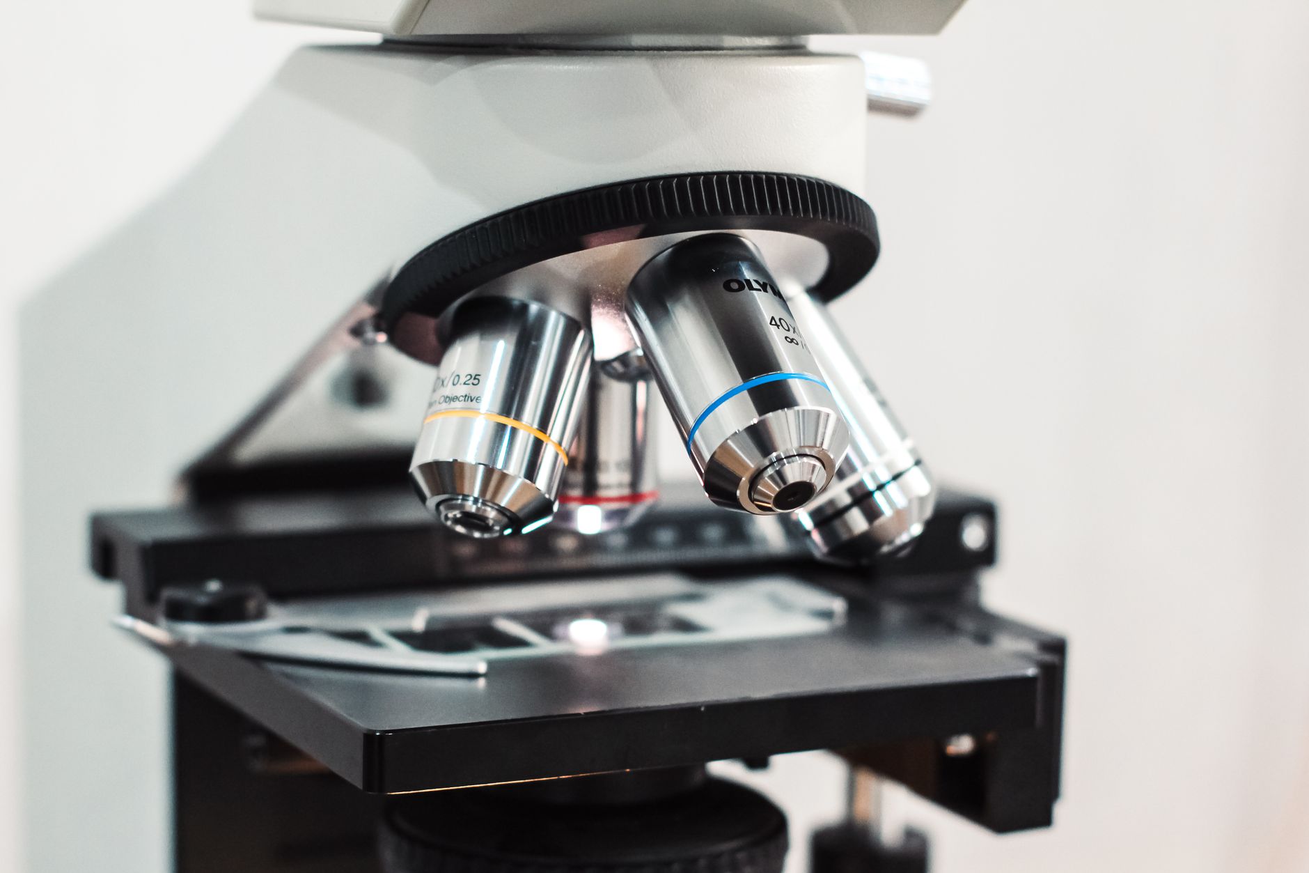 Detailed close-up of a microscope showing optical lenses on a light background.