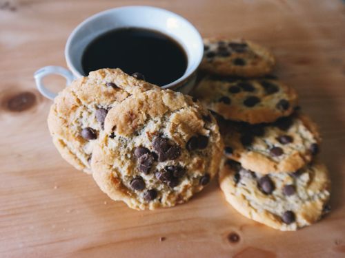 Free A cozy setup of chocolate chip cookies with a steaming cup of coffee. Stock Photo