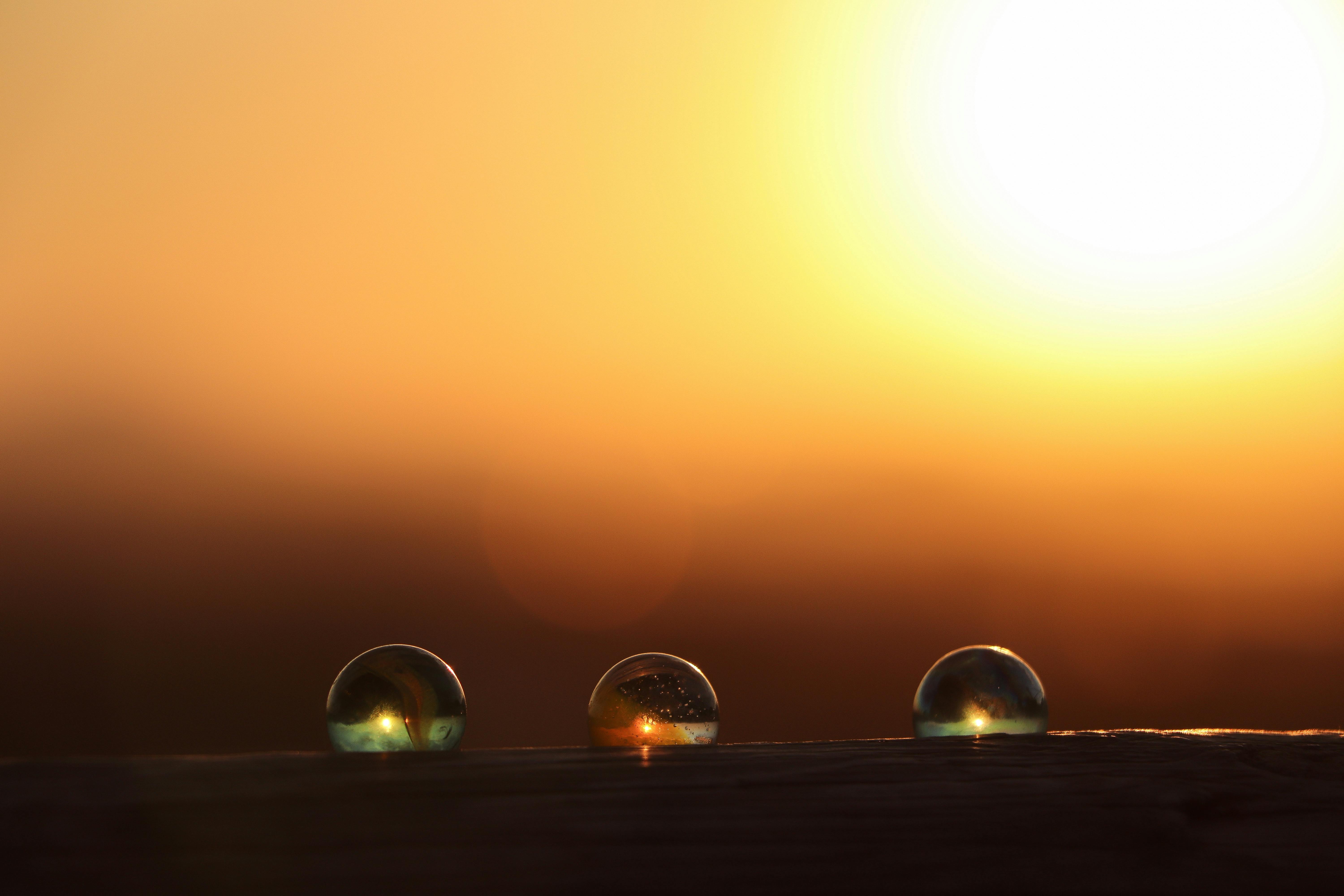 Close-up of dewdrops on a grass blade against a golden sunset background.