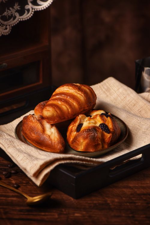 Free Golden pastries on a rustic black tray evoke a cozy, fresh morning atmosphere. Stock Photo