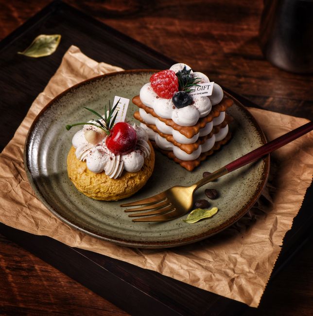 Delicate pastries artfully arranged with cream and berries on a rustic ceramic plate.