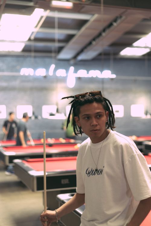 Free A young man with dreadlocks holding a cue stick in a stylish pool hall. Stock Photo