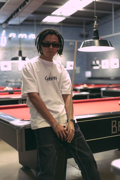 Free Fashionable young adult in sunglasses leaning on a pool table in a modern billiard hall. Stock Photo