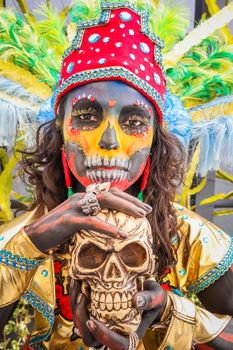 Colorful portrait of a woman with face paint holding a skull, celebrating Day of the Dead.