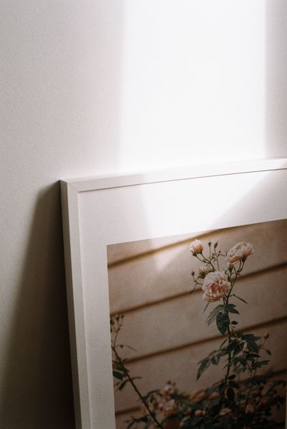 White-framed floral print leaning against a sunlit wall — photo by Tuba Nur Dogan on Pexels