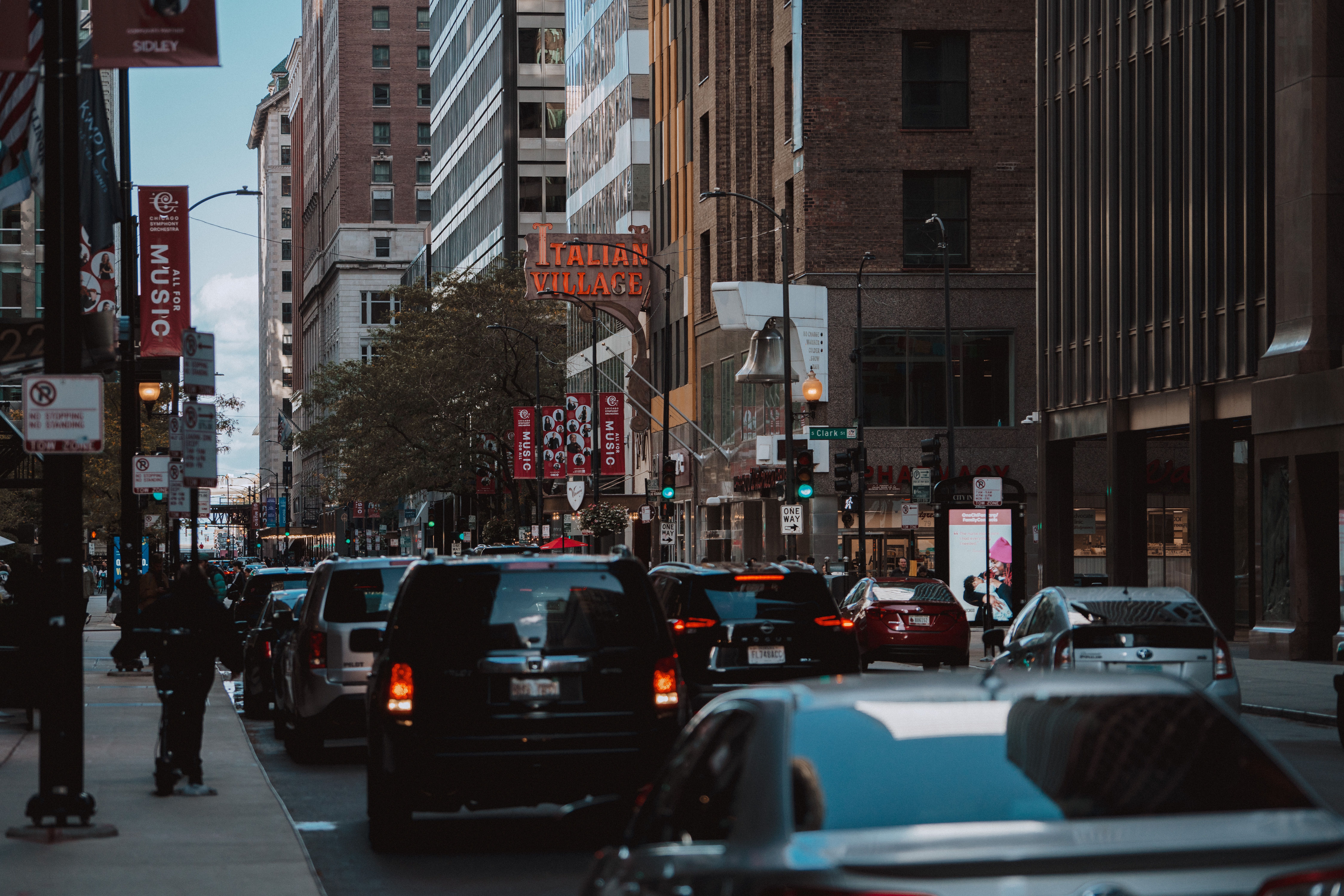 A bustling downtown street scene featuring traffic and pedestrians surrounded by tall buildings.