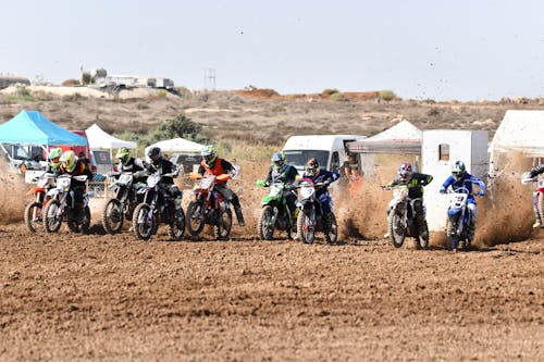 Group of Motorcycle Racers Starting at a Muddy Motocross Track