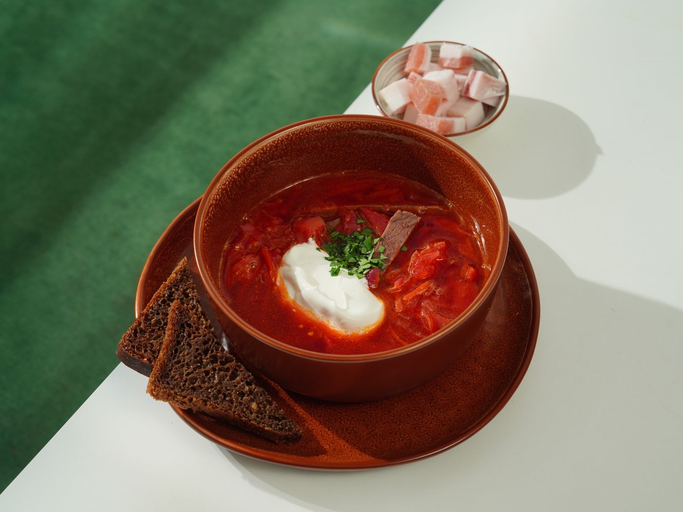 A flavorful bowl of borscht with sour cream and rye bread, perfect for any meal.