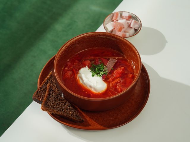A flavorful bowl of borscht with sour cream and rye bread, perfect for any meal.