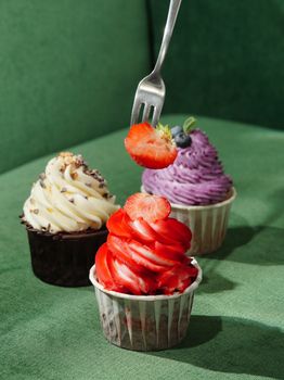 A delicious assortment of cupcakes featuring strawberry and blueberry toppings, perfect for dessert lovers.