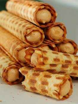 Mouth-watering close-up of cream-filled wafer rolls, perfect for dessert lovers.