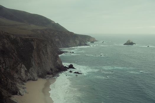 Breathtaking view of rugged cliffs meeting the ocean with waves crashing below.