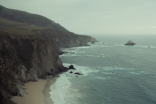 Free Breathtaking view of rugged cliffs meeting the ocean with waves crashing below. Stock Photo