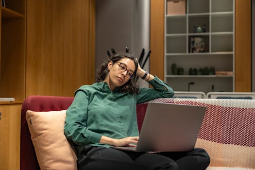 Woman in a cozy workspace relaxing with a laptop, reflecting modern remote work lifestyle.