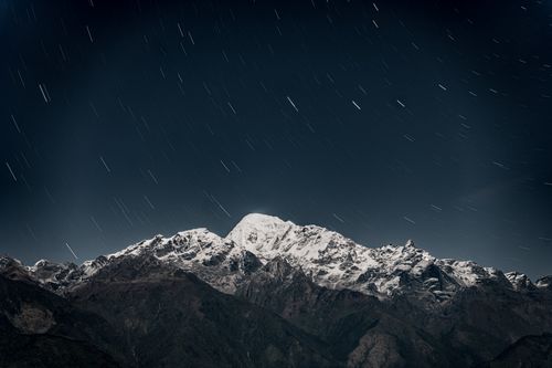 Free Nighttime long exposure capturing snowcapped Annapurna mountains with star trails in Gandaki Province, Nepal. Stock Photo