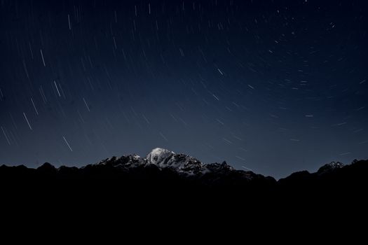 Dramatic long exposure of star trails over snowy mountains in Gandaki Province, Nepal.