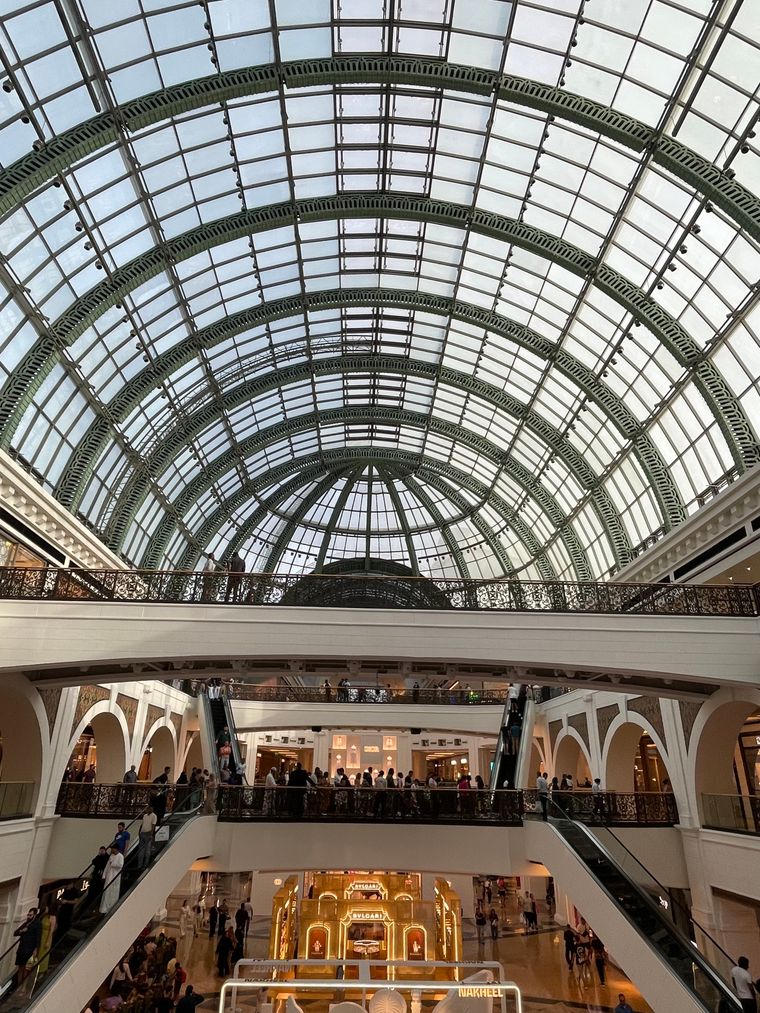 Grand marble-floored shopping mall interior with an arched glass ceiling in Dubai