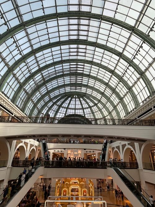Free Stunning interior view of Dubai shopping mall with grand arched glass ceiling and bustling shoppers. Stock Photo