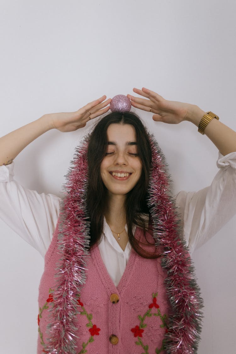 Smiling Woman With Tinsel Garland Around Her Neck And Christmas Bubble On Her Head